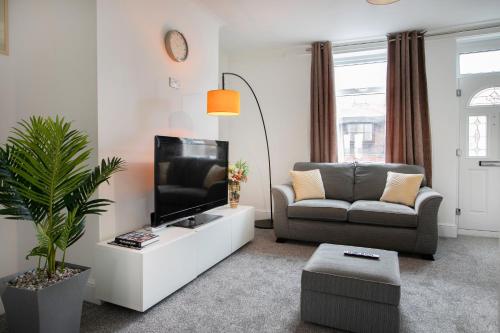a living room with a tv and a couch at Cudworth House, Barnsley for contractors & Families, off-road parking, speedy WIFI,etc in Barnsley