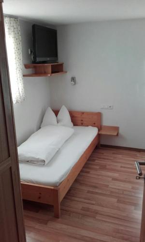 a bedroom with a bed with a tv on the wall at Gästehaus Obererlacher in Obertilliach
