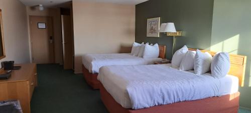 a hotel room with two beds and a couch at Travelodge by Wyndham Lacombe in Lacombe