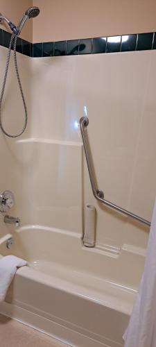 a bathroom with a bath tub with a shower at Travelodge by Wyndham Lacombe in Lacombe