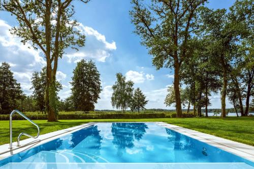 a swimming pool in a yard with trees at Villa Contessa - Luxury Spa Hotels in Bad Saarow