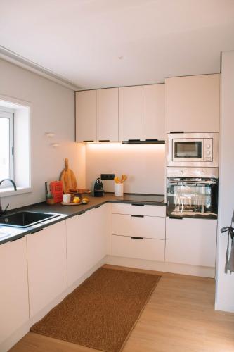 a kitchen with white cabinets and a microwave at Just Like Home - Moledo Slow Living in Moledo