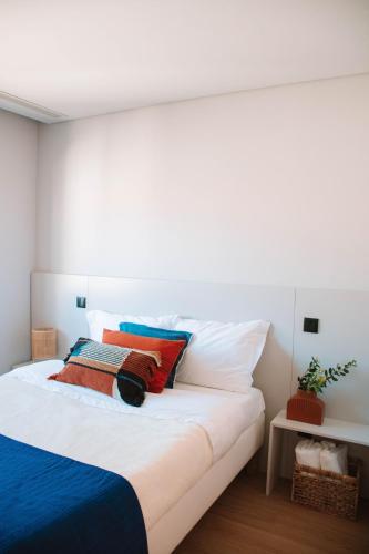 a bedroom with a large white bed with colorful pillows at Just Like Home - Moledo Slow Living in Moledo