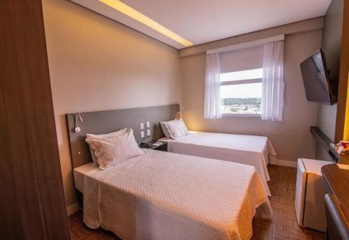 a hotel room with two beds and a window at Ramada by Wyndham Manaus Torres Center in Manaus