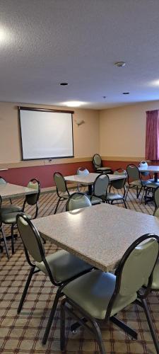 a classroom with tables and chairs and a projection screen at Travelodge by Wyndham Lacombe in Lacombe