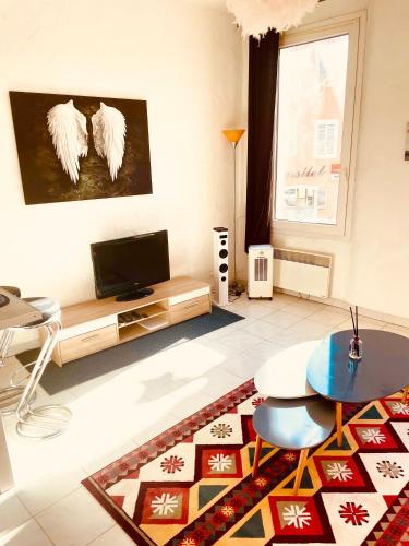 uma sala de estar com uma televisão, uma mesa e um tapete em So'Conciergerie -Studio situé dans le centre ville em Cassis