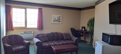 a living room with two chairs and a television at Travelodge by Wyndham Lacombe in Lacombe