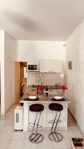 uma cozinha com um balcão e bancos num quarto em So'Conciergerie -Studio situé dans le centre ville em Cassis