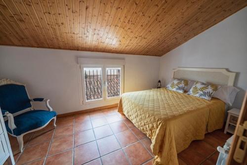 ein Schlafzimmer mit einem Bett und einem blauen Stuhl in der Unterkunft Casa rural collao de lobo in Serradilla