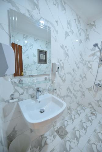 a white bathroom with a sink and a mirror at الدانة للشقق الفندقية in Kuwait