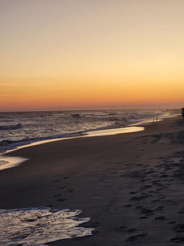 a sunset on a beach with footprints in the sand at Living the Dream 2 Bedroom Ocean View Cozy Condo in Gulf Shores