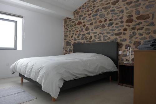 1 dormitorio con cama y pared de piedra en La Grange, Gîte 4 à 6 pers avec vue en Saint-Just-près-Brioude