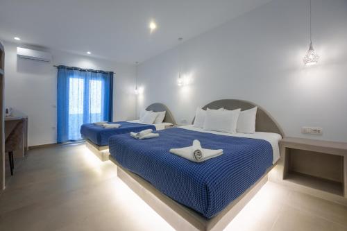 two beds in a room with blue sheets and towels at Anna's in Karterados