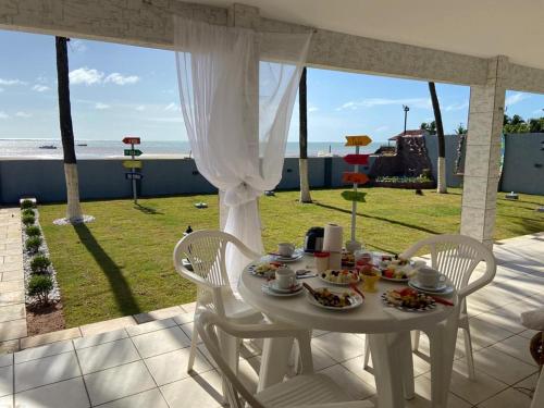 una mesa blanca con comida y vistas a la playa en Casa Pé na Areia, en São José da Coroa Grande
