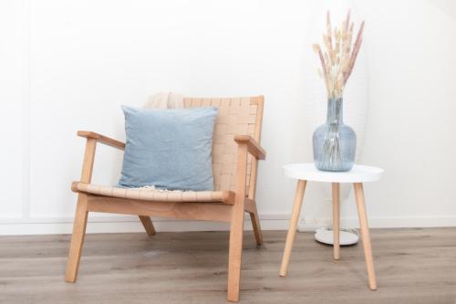 a wooden chair with a blue pillow next to a table at Löwe Apartment Blau Neuhausen am Rheinfall in Neuhausen am Rheinfall