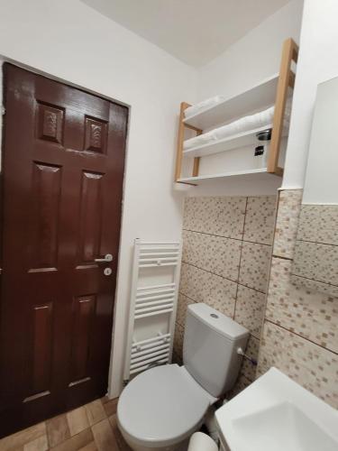 a bathroom with a toilet and a brown door at Casa Rusu -Moroasa-Self check in-24h Netflix in Reşiţa