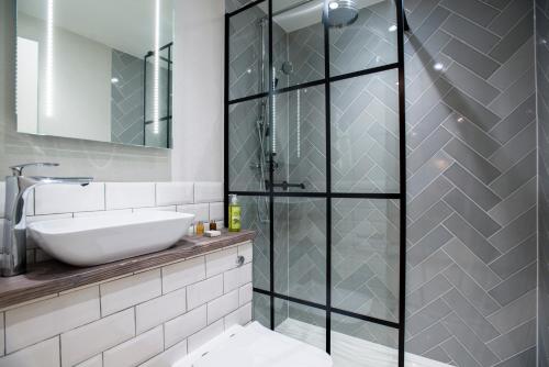 a bathroom with a glass shower stall and a sink at The Lodge Duxford in Duxford