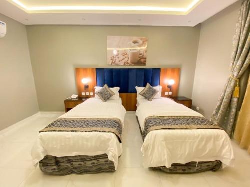 two beds in a hotel room with two lamps at أزار للشقق الفندقية in Abyār ‘Alī