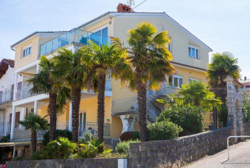 a yellow building with palm trees in front of it at Luxury apartments Vanessa, Njivice in Njivice