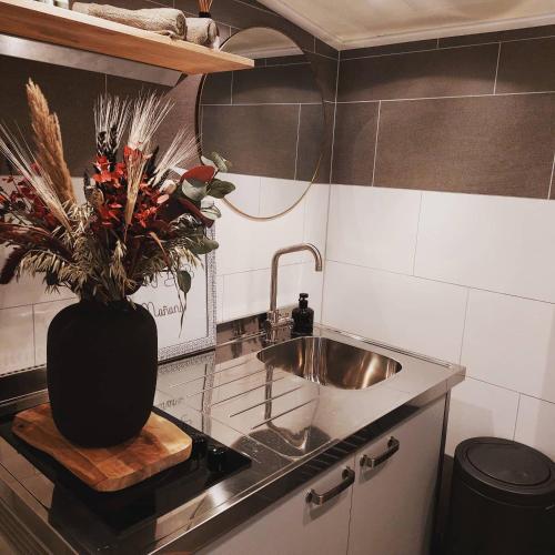 a kitchen with a sink and a vase of flowers at Studio Mañana in Cuijk