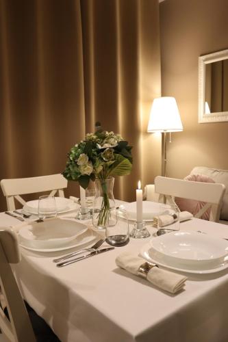 a white table with a vase of flowers on it at A Casa Tua in Bologna
