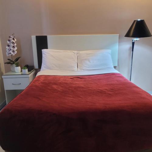 a bedroom with a large bed with a red blanket at Hotel Cali Blvd. in Guadalupe