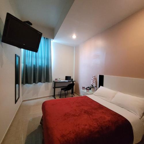 a bedroom with a bed and a desk with a television at Hotel Cali Blvd. in Guadalupe