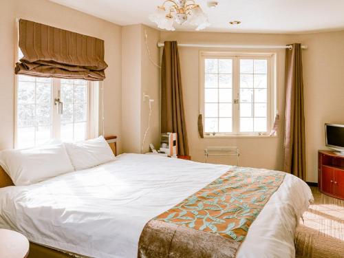 a bedroom with a large white bed and two windows at Hakuba Sun Valley Hotel Annex - Vacation STAY 90337v in Iida