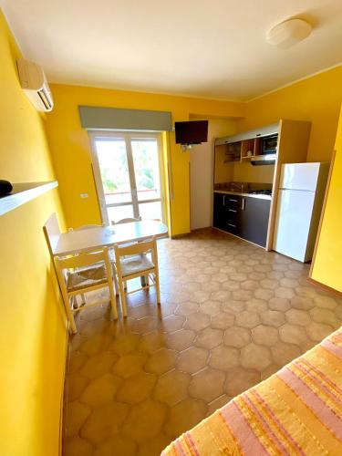a room with a table and a kitchen with yellow walls at Residence Hotel Felix in Ricadi