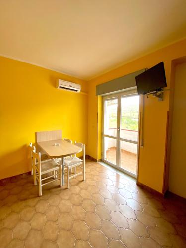 a dining room with yellow walls and a table and a television at Residence Hotel Felix in Ricadi