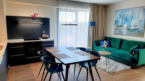 sala de estar con sofá verde, mesa y sillas en Ferienwohnung A102 mit Komfort in Strandnähe mit Terrasse und Meerblick in 10ter Etage PARKING FREE en Międzyzdroje