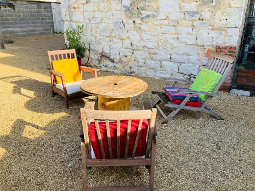 drie stoelen en een houten tafel en twee stoelen bij Gîte les Tilleuls in Le Guédéniau