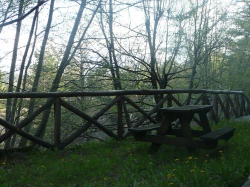 a bench in the grass next to a wooden bridge at Villaggio Barilari in Minucciano