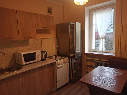 a kitchen with a microwave and a stove and a window at Кульпарківська 128,економ in Lviv