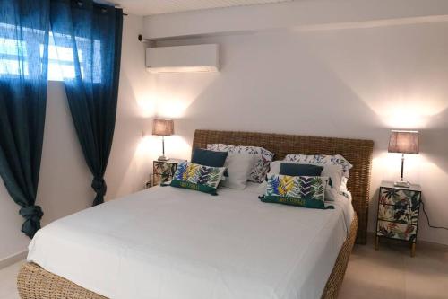 - une chambre avec un grand lit blanc et des rideaux bleus dans l'établissement EBENE, à Sainte-Luce