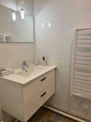 Baño blanco con lavabo y espejo en Cosy appartement entre Paris et Disneyland, en Le Perreux-Sur-Marne