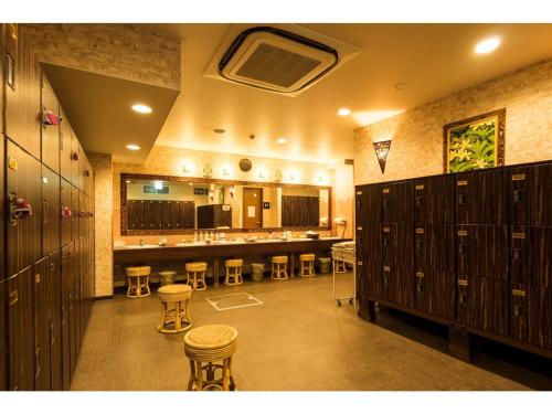 Hotel Areaone Hiroshima Wing - Vacation STAY 62261v في هيغاشيهيروشيما: غرفة كبيرة مع خزانات وكراسي في صالة ألعاب رياضية