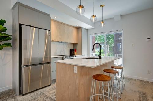 a kitchen with a refrigerator and two bar stools at Amazing 1Bedroom Great Location presented by TripMontreal in Montreal
