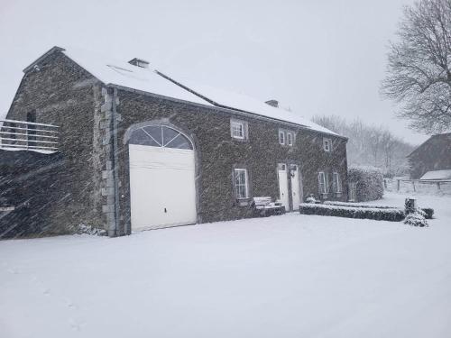a barn with a white garage door in the snow at Gîte Le Haut des Vannes in Neufchâteau