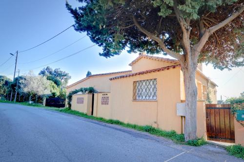 une maison avec un arbre sur le côté d'une rue dans l'établissement La farigoulette, à Rayol-Canadel-sur-Mer