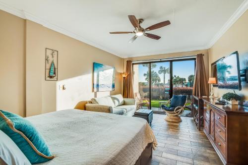 a bedroom with a bed and a couch and a ceiling fan at Pirates Bay A113 in Fort Walton Beach
