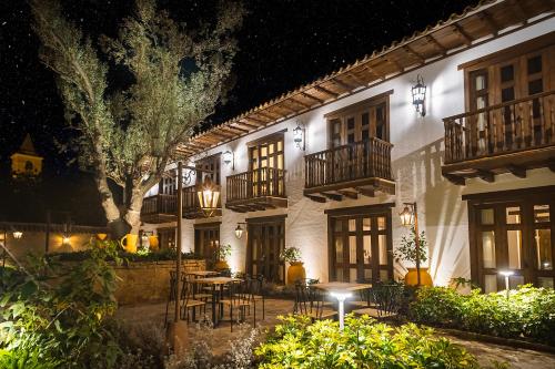 a building with tables and chairs in a courtyard at night at Hotel Casa Alcestre in Villa de Leyva