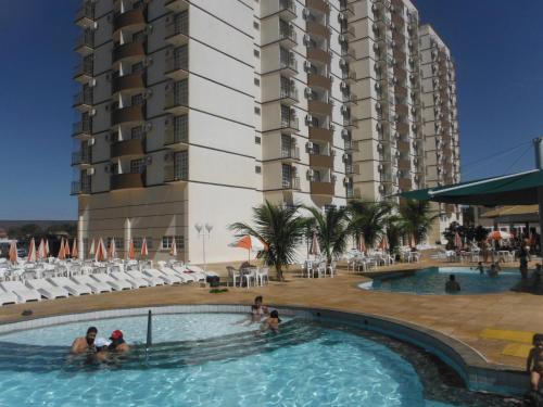 a group of people in a swimming pool next to a tall building at Diroma Exclusive Flats Para Temporada in Caldas Novas