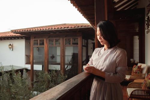 a woman standing on the balcony of a house at Hotel Casa Alcestre in Villa de Leyva