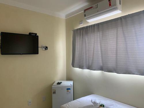 a room with a tv on the wall and a bed at Floripa Flat in Areia Branca