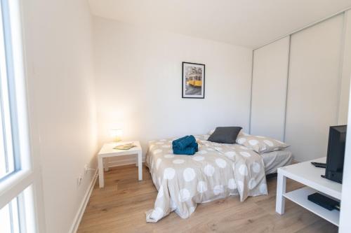 een witte slaapkamer met een bed en een televisie bij LE DAUPHIN - Place parking privée gratuit - WIFI et TV in Saint-Étienne
