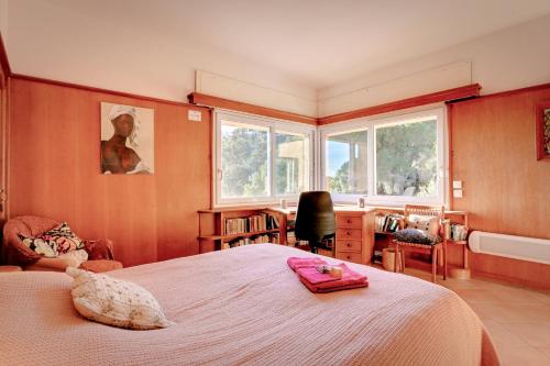 a bedroom with a bed and a desk and windows at Les Iles D'Or in Rayol-Canadel-sur-Mer