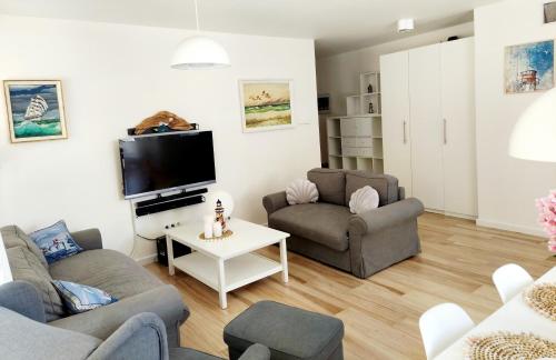 a living room with two couches and a tv at Apartament Morze Sztuki, Jantar in Jantar