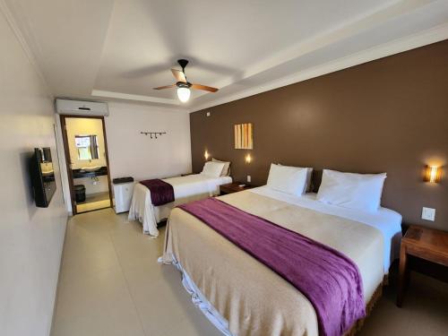 a hotel room with two beds and a ceiling fan at Pousada Camarás in Alto Paraíso de Goiás