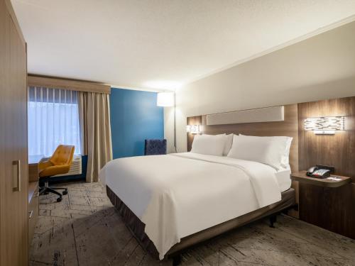 a hotel room with a large bed and a chair at Holiday Inn Express & Suites Greensboro - I-40 atWendover by IHG in Greensboro